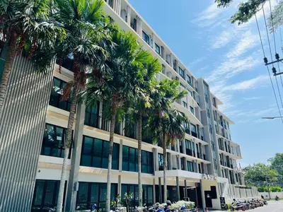 a large building with palm trees in front of it at Zcape 2 Phuket by RESAVA in Bang Tao Beach