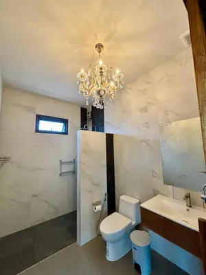 a bathroom with a chandelier and a toilet and a sink at Seashine Private Pool Villa at Klong Muang in Klong Muang Beach