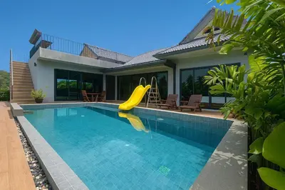 a swimming pool with a slide in front of a house at Seashine Private Pool Villa at Klong Muang in Klong Muang Beach