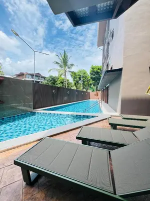 a swimming pool with two picnic tables in front of a building at The Legacy V Beachfront Resort Ao Nang Krabi, Aspira Collection - Adults only in Ao Nang Beach