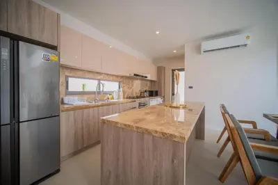 a kitchen with a stainless steel refrigerator and wooden cabinets at 3BR Villa Z by NLA in Bang Tao Beach