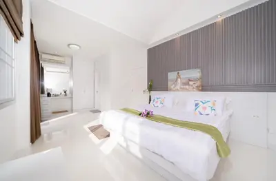 a white bedroom with a large bed with flowers on it at Laguna Townhouse with private pool and your own gym near Bangtao Beach in Laguna Phuket