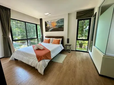 a bedroom with a large bed and large windows at Apartment Title I, Rawai Phuket in Rawai Beach