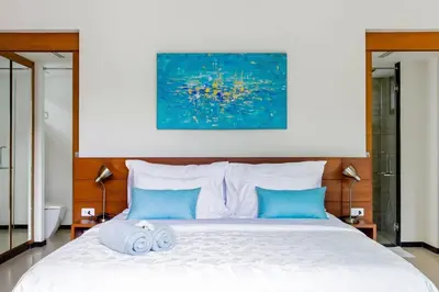 a bedroom with a large white bed with blue pillows at Serene Contemporary Villa with a Swimming Pool in Ban Saiyuan (1)