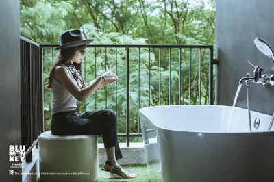 a woman sitting on a stool next to a bath tub at Blu Monkey Hub and Hotel Phuket Town- Free All Day Coworking space in Phuket Town