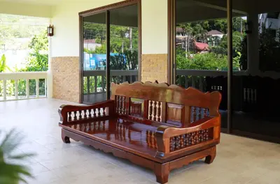 a wooden bench sitting in the middle of a porch at Вилла с 6 спальнями в районе Раваи in Ban Suan