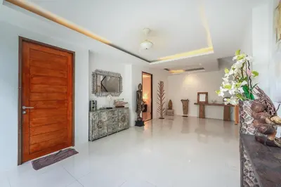 a hallway with a wooden door and a white tile floor at V210 Retreat 3BR Top of the Range, Sea View,Lift in Rawai Beach