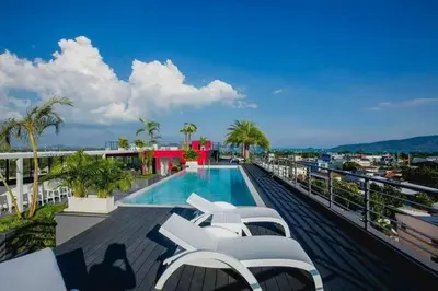 a balcony with a swimming pool and lounge chairs at C212 Relaxing Condo Rooftop Pool & Ocean Views in Chalong