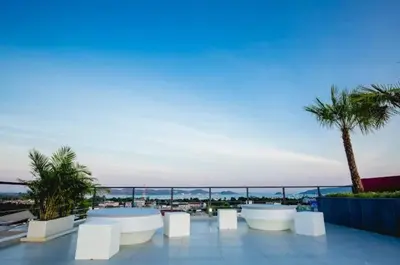 a patio with white benches and a view of the ocean at C212 Relaxing Condo Rooftop Pool & Ocean Views in Chalong