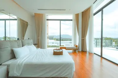 a bedroom with a white bed and large windows at Zavaya Luxury Private Pool Villa Phuket in Layan Beach