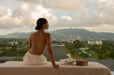 a woman sitting on a table looking out at the city at Zavaya Luxury Private Pool Villa Phuket in Layan Beach