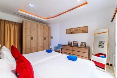 a bedroom with a large white bed with red pillows at Exotic 3BR Villa Solandra with Tropical Pool and Private Rooftop Terrace in Bangtao in Bang Tao Beach