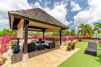 a pavilion with couches and flowers in a garden at Exotic 3BR Villa Solandra with Tropical Pool and Private Rooftop Terrace in Bangtao in Bang Tao Beach
