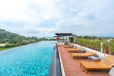 a row of chairs sitting on the edge of a swimming pool at C209 Surin Beachside Sun Escape & Infinity Pool in Surin Beach
