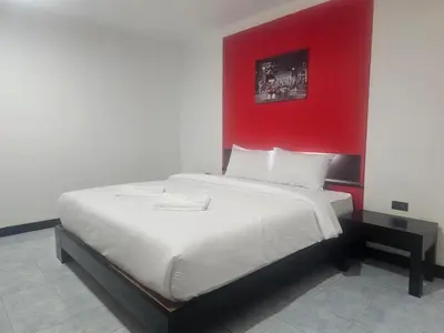a bedroom with a large bed with a red wall at Patong Central Budget Stay in Patong Beach