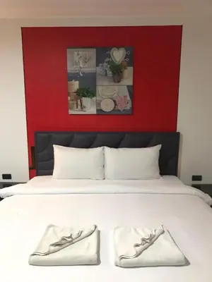 a bed with a red headboard and two white shoes at Patong Central Budget Stay in Patong Beach