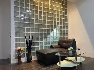 a living room with a leather couch and a glass wall at Patong Central Budget Stay in Patong Beach