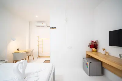 a white room with a bed and a tv at ZJ House Phuket Town in Phuket Town