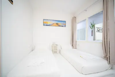 three beds in a white room with a window at ZJ House Phuket Town in Phuket Town