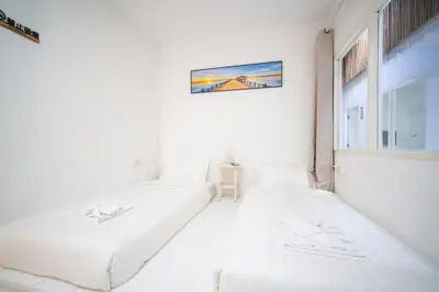 two beds in a room with a window at ZJ House Phuket Town in Phuket Town