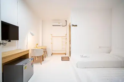 a white room with a bed and a desk at ZJ House Phuket Town in Phuket Town
