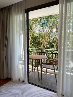 a sliding glass door with a table and a bench on a balcony at Brand new apartment on Kamala in Kamala Beach