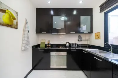 a kitchen with black cabinets and a sink at Laguna Townhouse with private pool, Bang Tao Beach in Laguna Phuket