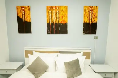 a bedroom with a bed with three paintings on the wall at 3 Bed 3 Bath Villa 400m to Beach in Surin Beach