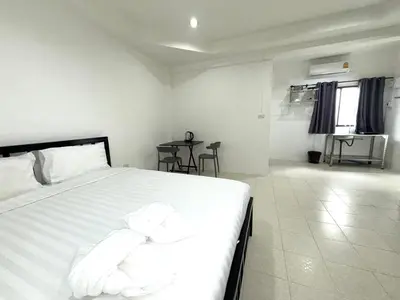 a bedroom with a bed with white sheets and a table at Patong Canal Villa 104 in Patong Beach