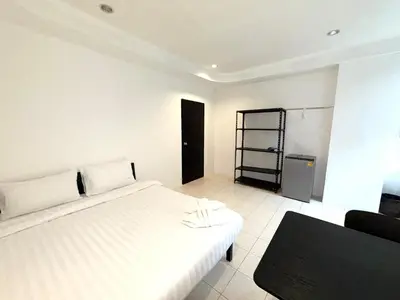 a bedroom with a white bed and a black chair at Patong Canal Villa 105 in Patong Beach