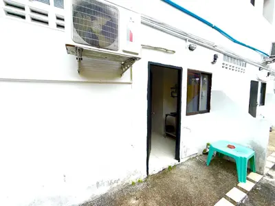 a white building with a door and a green bench at Patong Canal Villa 105 in Patong Beach