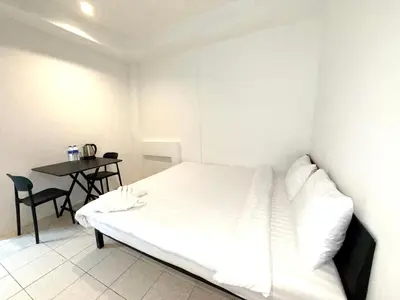 a white bedroom with a bed and a table at Patong Canal Villa 105 in Patong Beach