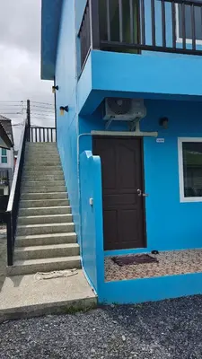 a blue building with stairs leading up to a door at GN House Bangtao in Ban Thalat Choeng Thale