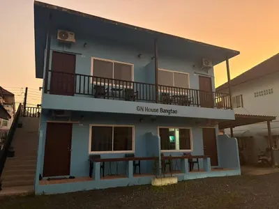 a blue building with a balcony and a table at GN House Bangtao in Ban Thalat Choeng Thale