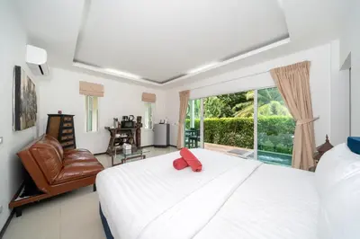 a bedroom with a bed and a chair and a window at Oxavia Garden Oasis B3 in Nai Harn with Jaccuzzi in Rawai Beach