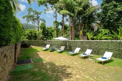 a row of lounge chairs in a yard next to a wall at Oxavia Garden Oasis B3 in Nai Harn with Jaccuzzi in Rawai Beach