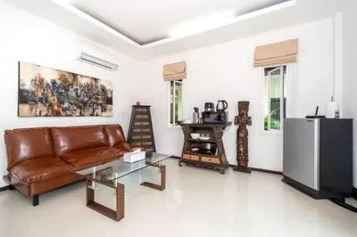 a living room with a leather couch and a television at Oxavia Garden Oasis B3 in Nai Harn with Jaccuzzi in Rawai Beach