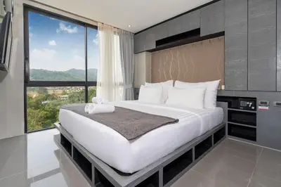 a bedroom with a large bed with a large window at Tropics Kamala Hill View Suite CTG L605, near Kamala Beach and Fantasea in Kamala Beach