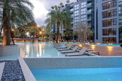 a swimming pool with lounge chairs and palm trees at Tropics Kamala Hill View Suite CTG L605, near Kamala Beach and Fantasea in Kamala Beach