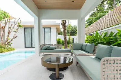 a patio with a couch and a coffee table next to a pool at Mouana Breeze Mai Khao 4-bedroom Pool Villa 9919 in Mai Khao Beach