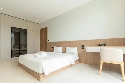 a bedroom with a white bed and a white chair at Mouana Breeze Mai Khao 4-bedroom Pool Villa 9919 in Mai Khao Beach