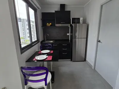 a small kitchen with a table and a refrigerator at Sleek Corner 1 Bed Apt T1-607 in Chalong