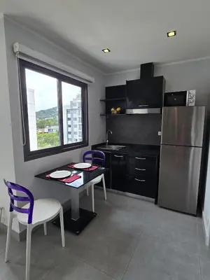 a kitchen with a table and chairs and a refrigerator at Sleek Corner 1 Bed Apt T1-607 in Chalong