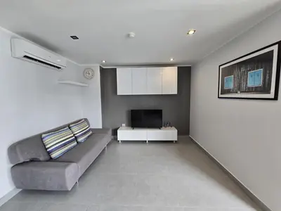 a living room with a couch and a tv at Sleek Corner 1 Bed Apt T1-607 in Chalong