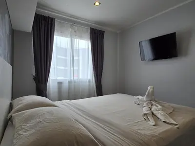 a bedroom with a bed with a television on the wall at Sleek Corner 1 Bed Apt T1-607 in Chalong