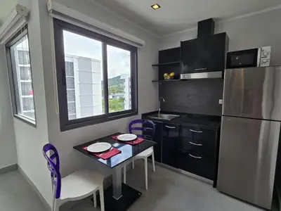 a small kitchen with a table and a refrigerator at Sleek Corner 1 Bed Apt T1-607 in Chalong