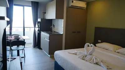 a bedroom with a bed and a table and a kitchen at Blue Edge Studio T3-527 in Chalong