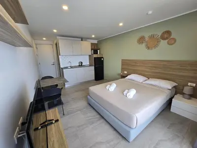 a bedroom with a large bed and a kitchen at Modern Studio Apt T3-526 in Chalong