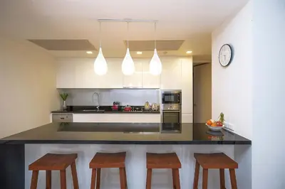 a kitchen with a counter with chairs and a clock at Stunning Seaview Escape - Modern and Elegant in Kata Beach