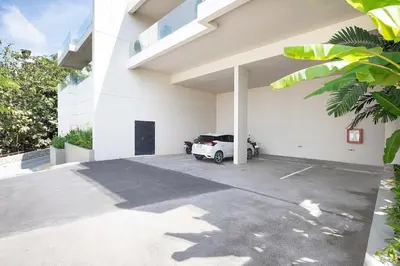 a white building with a car parked in a parking lot at Stunning Seaview Escape - Modern and Elegant in Kata Beach